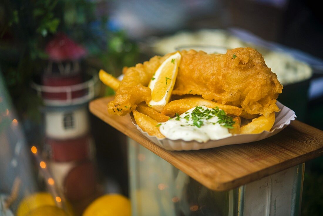 Fish and chips with remoulade in a paper dish