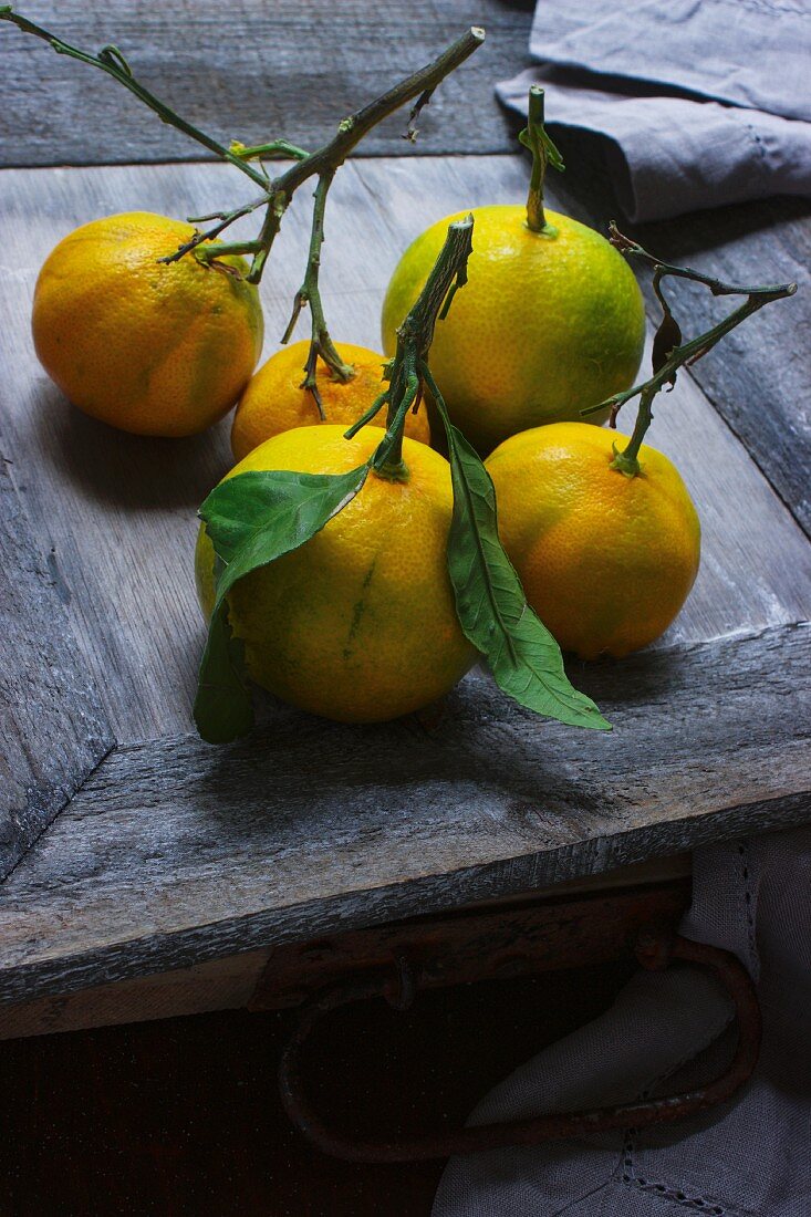 Mehrere Mandarinen mit Blättern auf Holztisch