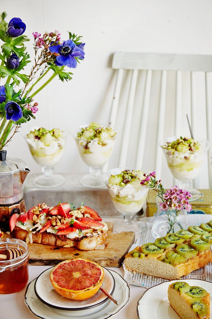 A breakfast buffet with yoghurt cups, cake, toast and grapefruit