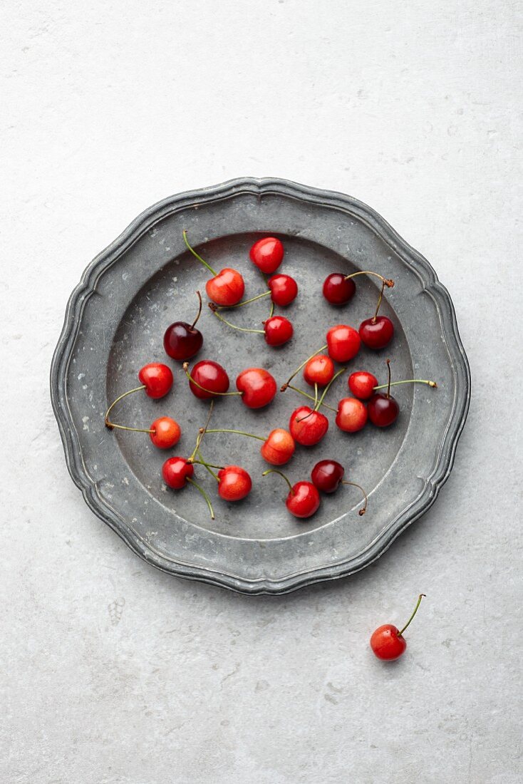 Fresh cherries on a vintage metal plate (seen from above)