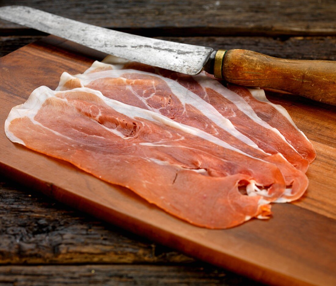 Slices of Parma ham on a wooden chopping board