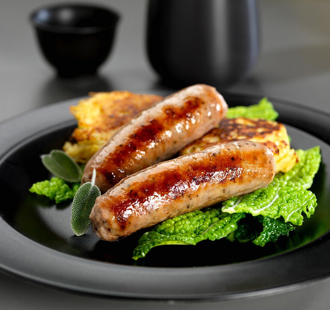 Pork and herb sausages with Savoy cabbage and potato fritters