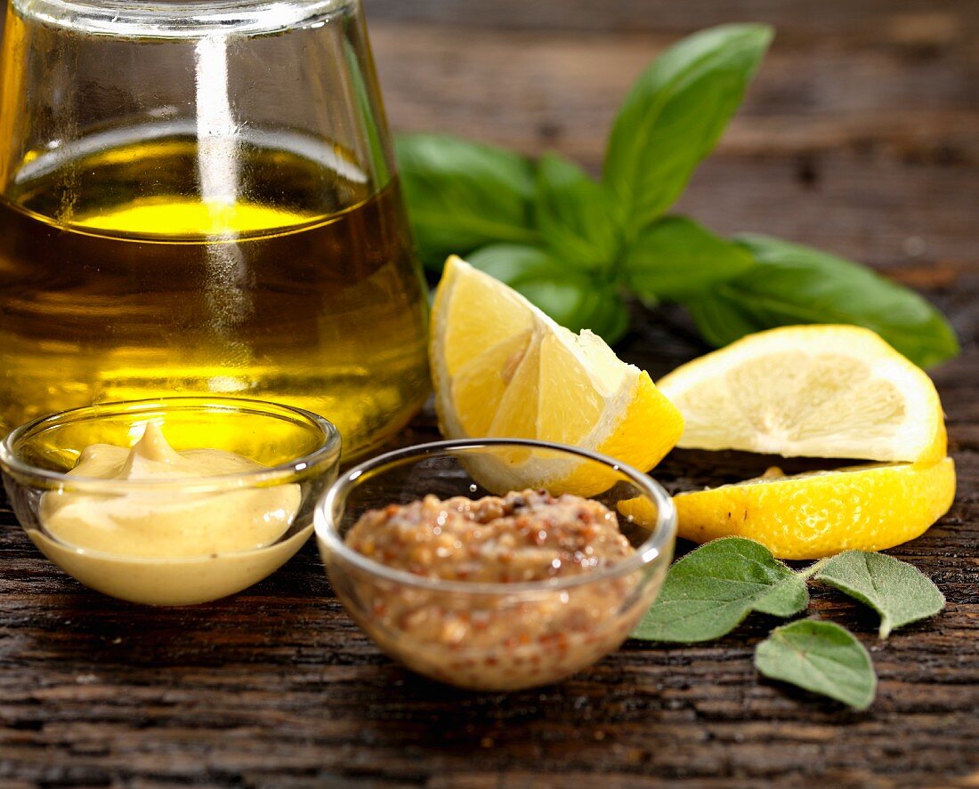 Zutaten für eine Salatsauce mit Olivenöl, Dijon-Senf, scharfem Senf, Zitrone, Basilikum und Salbei
