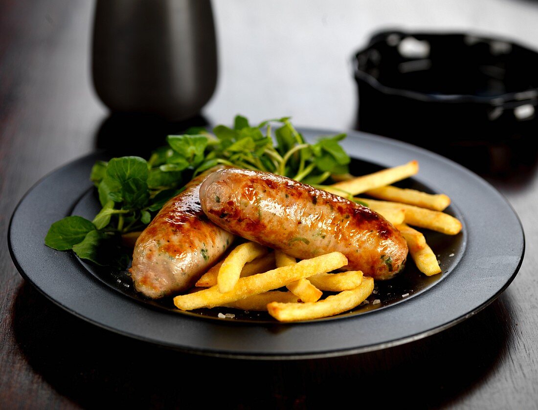 Fried pork and ale sausages with French fries and watercress