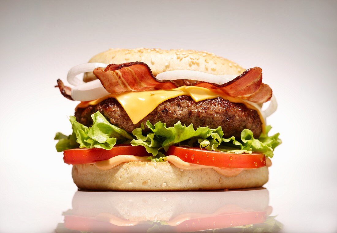 A bacon cheeseburger on a white surface