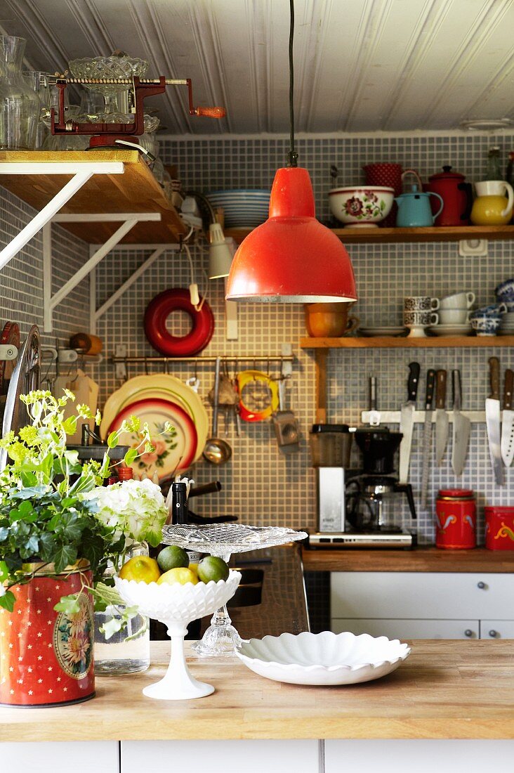 Corner of vintage-style kitchen with red pendant lamp above counter and utensils hung on wall