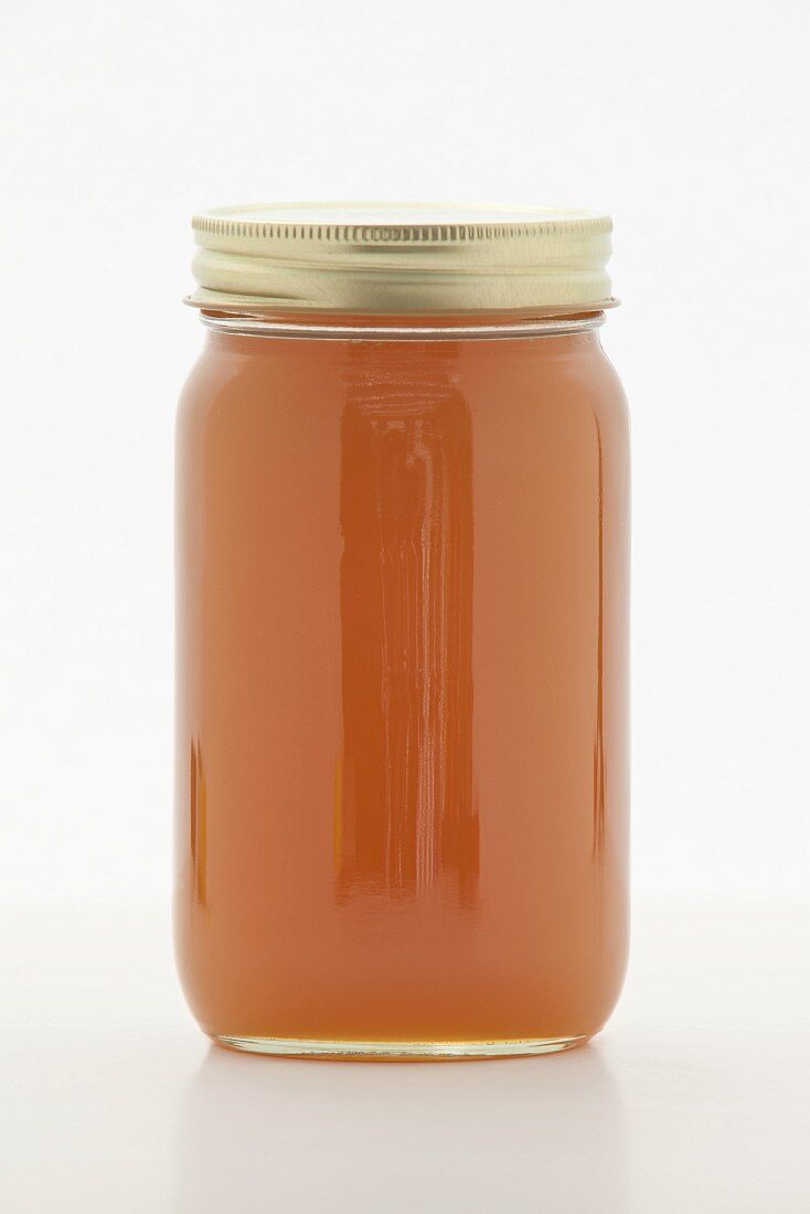 Brown rice syrup as sugar replacement in a screw-top jar on a white surface