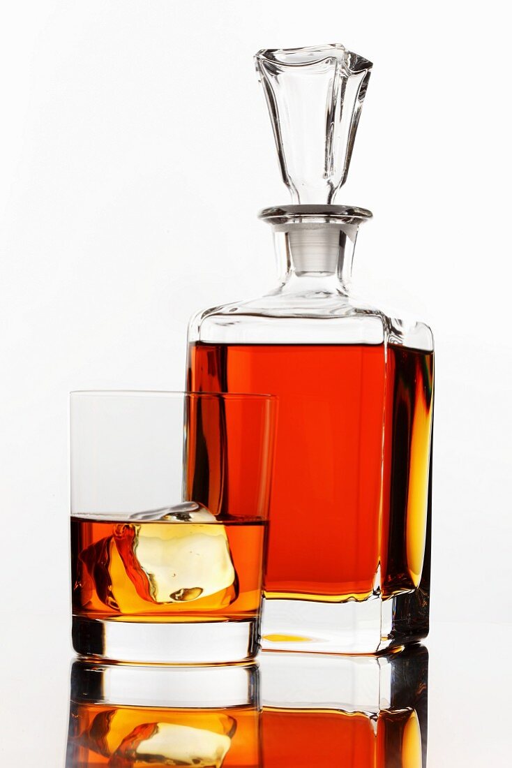 Whiskey in a glass and a bottle on a white surface