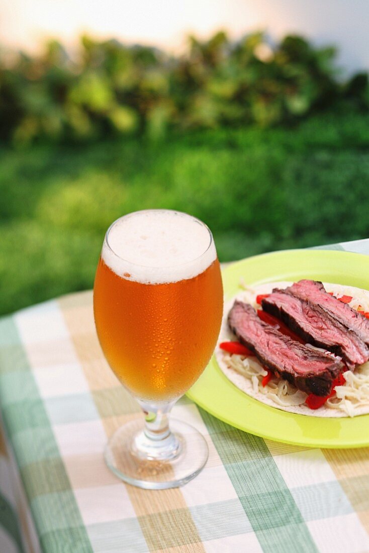 A glass of Largo on a garden table with a plate of beef on a cabbage salad