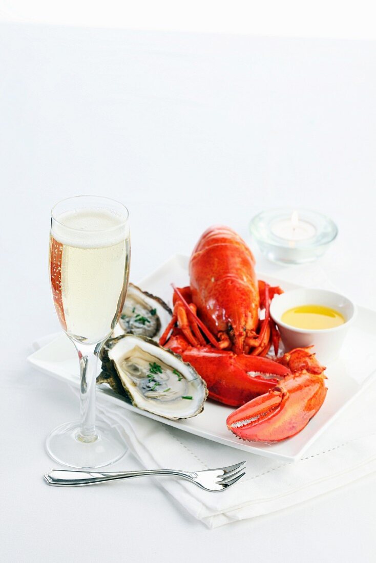 Cooked lobster with butter and oysters on a serving platter with champagne