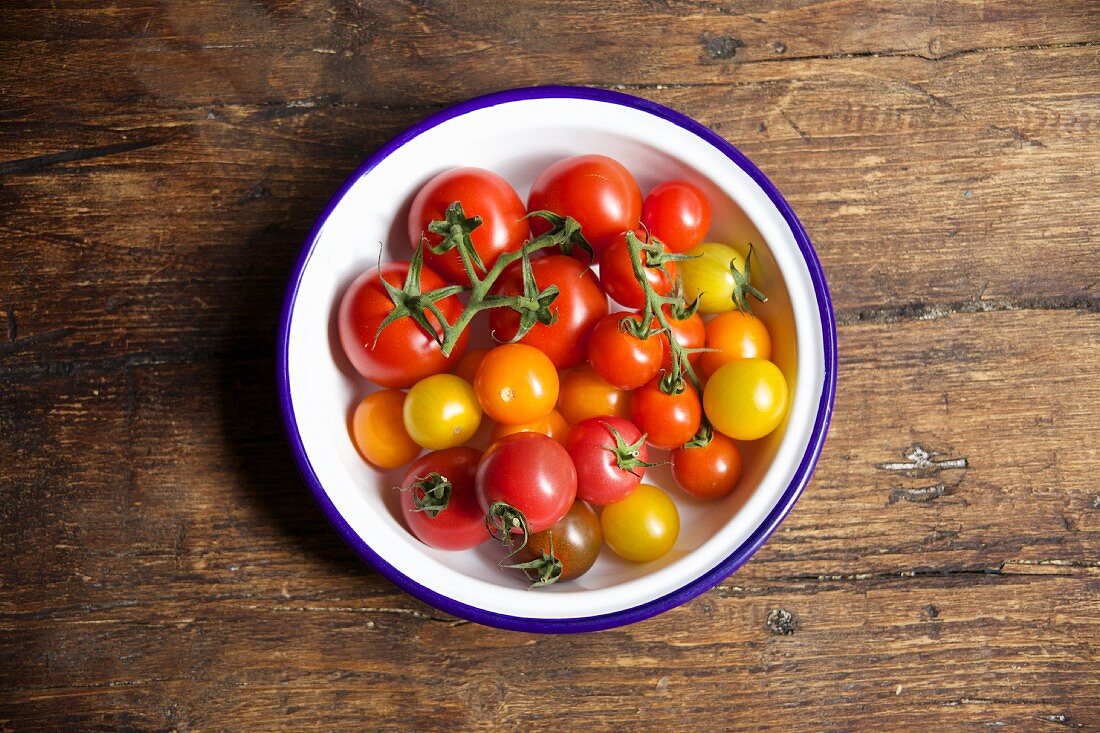 Various tomatoes in bowl on a wooden table
