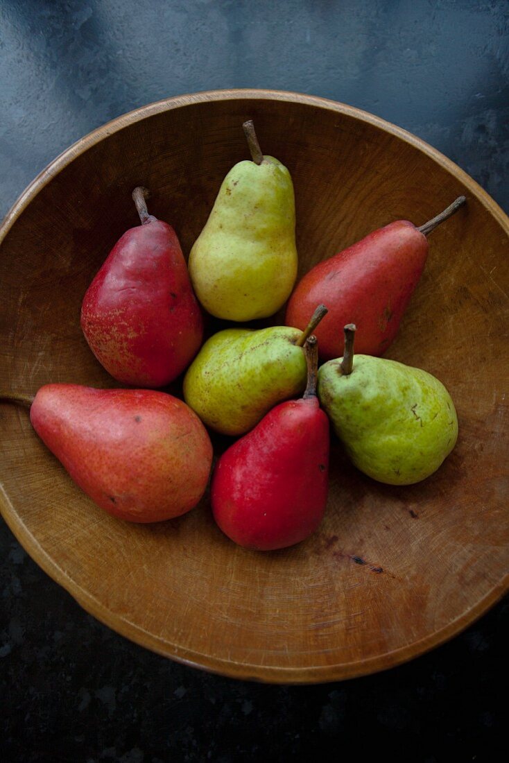 Various types of pears in a wooden bowl