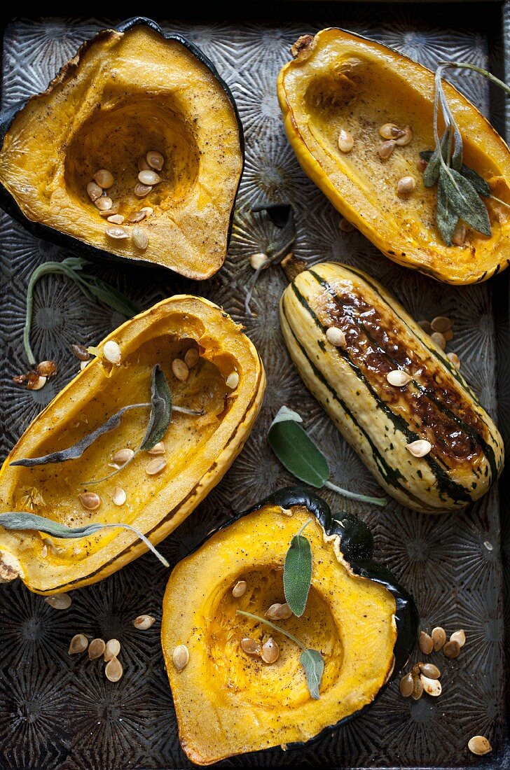 Roasted hollowed-out pumpkin with pumpkin seeds and sage on an antique baking tray