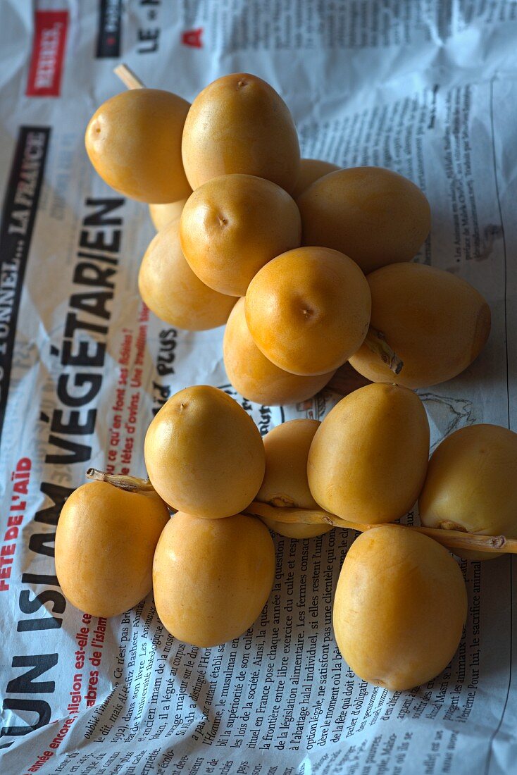 Fresh yellow dates from a market on a piece of newspaper