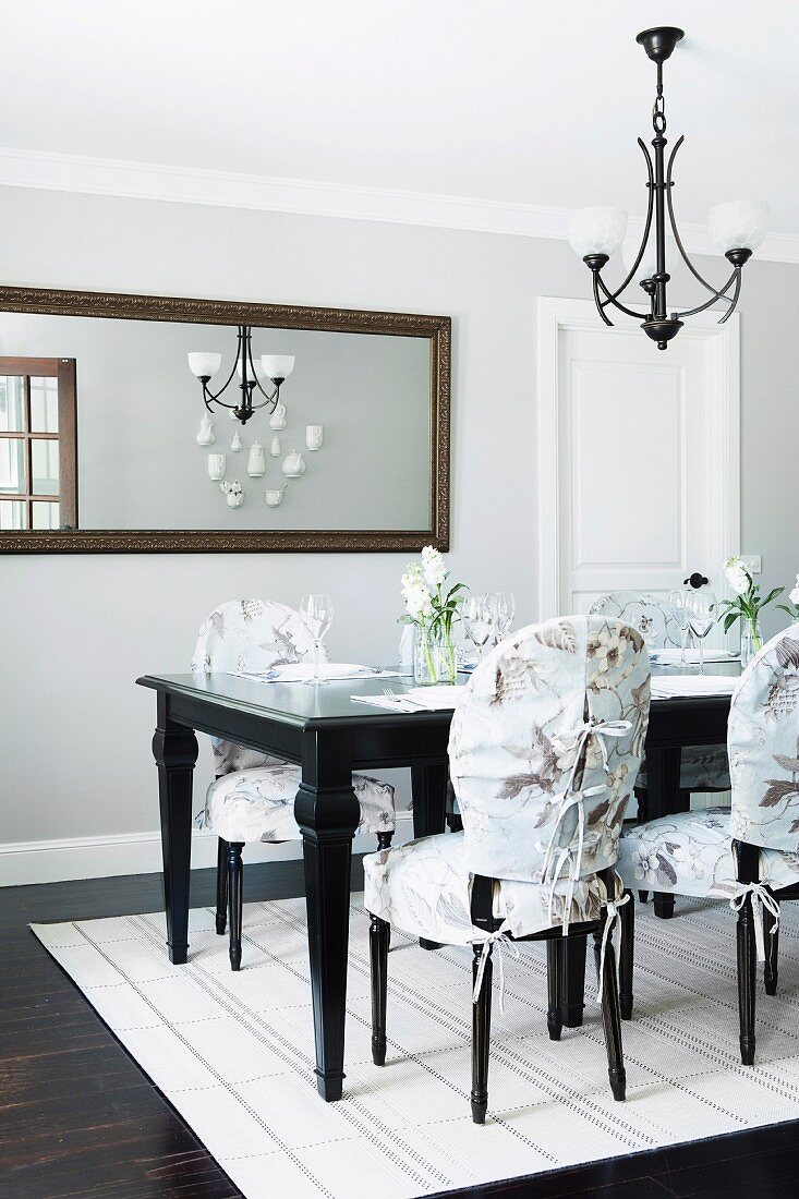 Stühle mit gemusterter Husse an schwarzem Tisch in elegantem Esszimmer