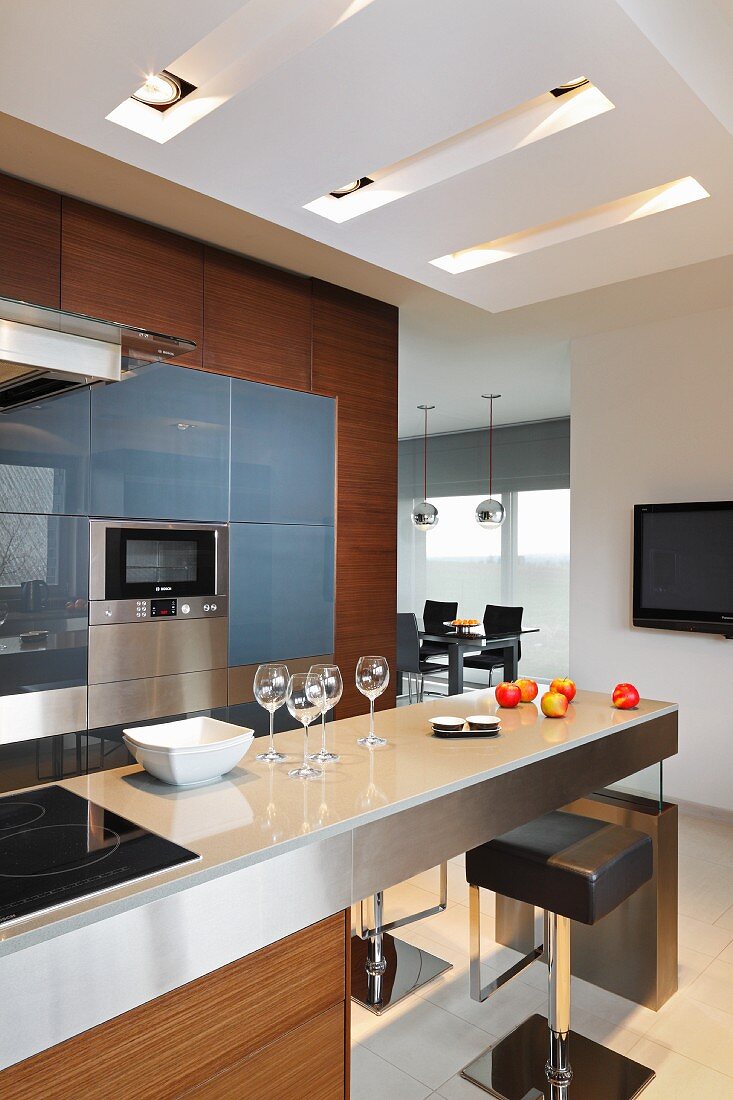 Elegant designer kitchen with breakfast bar and view into open-plan dining area