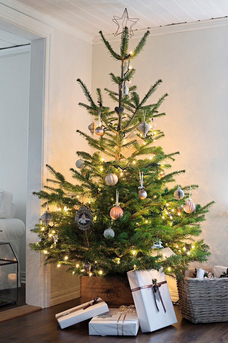 Christmas tree decorated with fairy lights surrounded by simply wrapped gifts