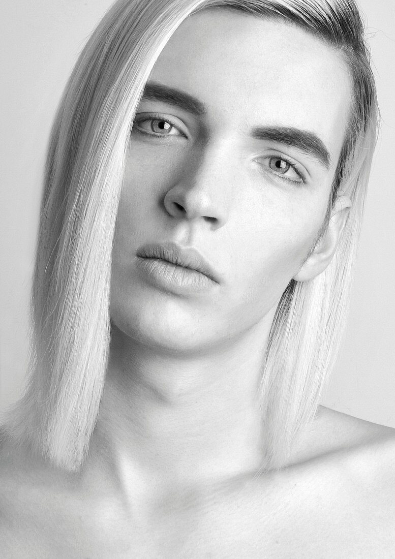 Androgyner junger Mann mit langen blonden Haaren (s/w-Foto)