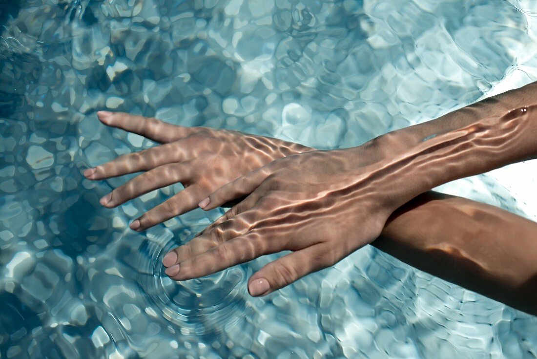 A woman's hands under water in a pool