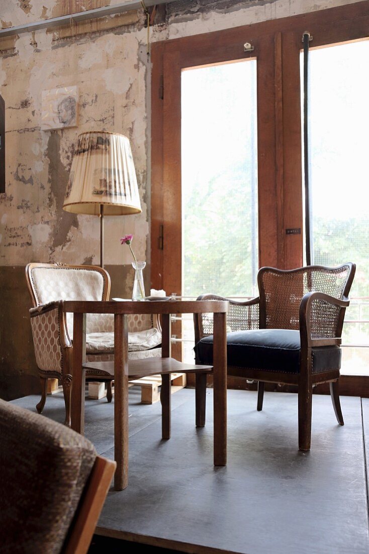 Armchairs at wooden table and vintage standard lamp against unrendered wall in Café Hutmacher, Wuppertal, German