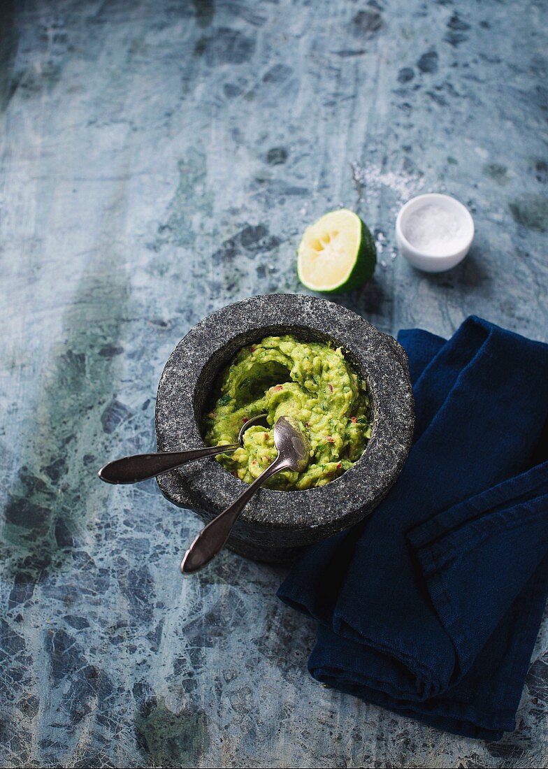 Guacamole in a mortar with spoons