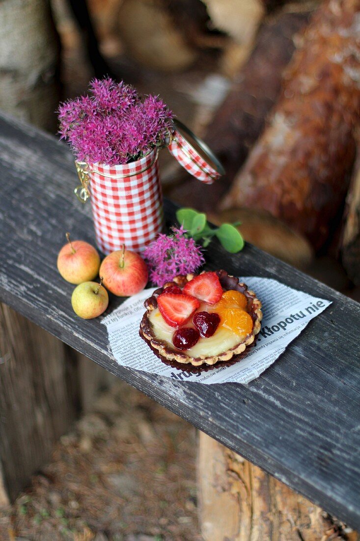 A fruit tartlet on a wooden bench in a garden