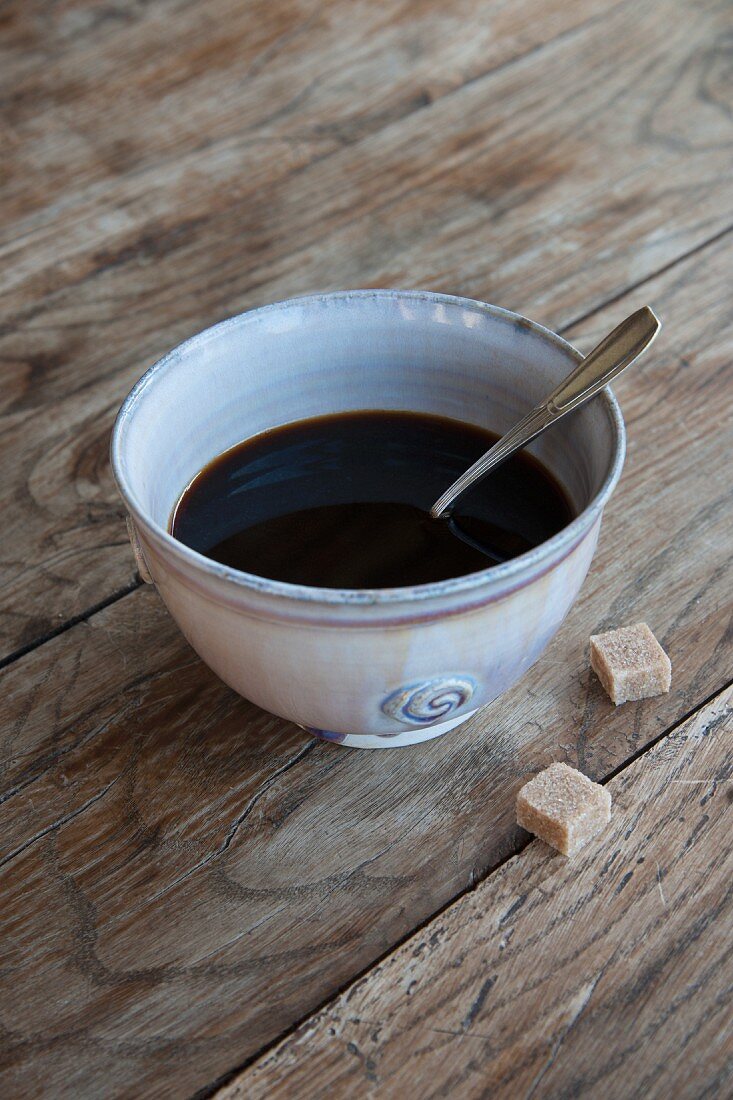 Black coffee in a ceramic bowl with a spoon