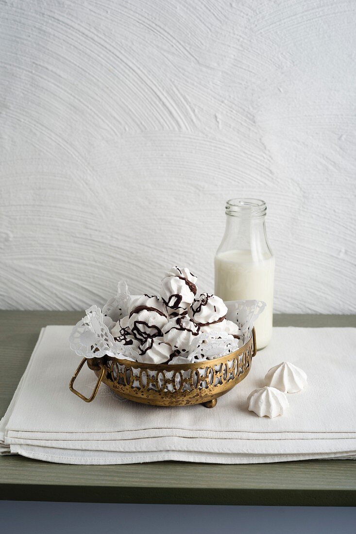 Meringues with chocolate glaze next to a bottle of milk