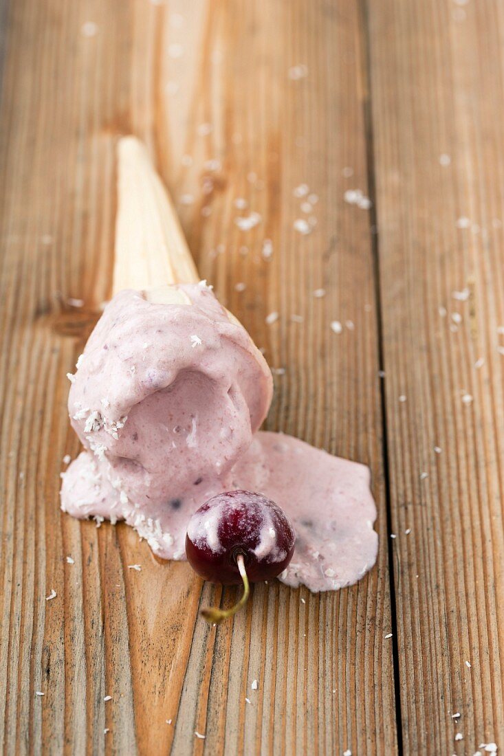 Melted cherry ice cream in a cone with grated coconut