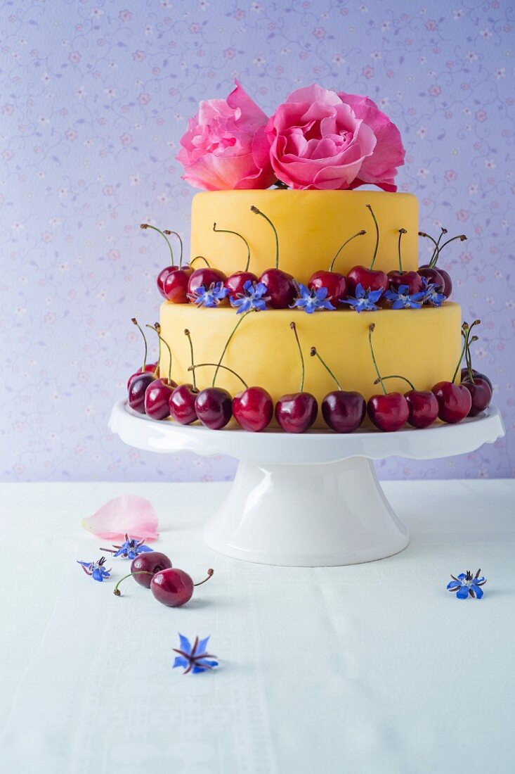 A two tier fondant cake decorated with flowers and cherries