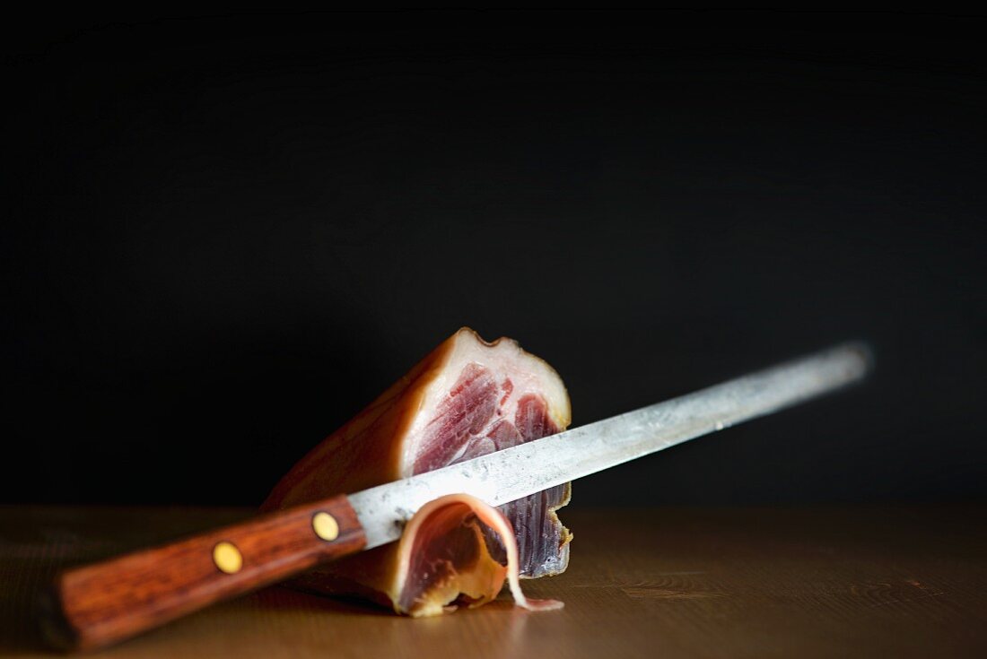 The end of a whole Prosciutto with a ham knife