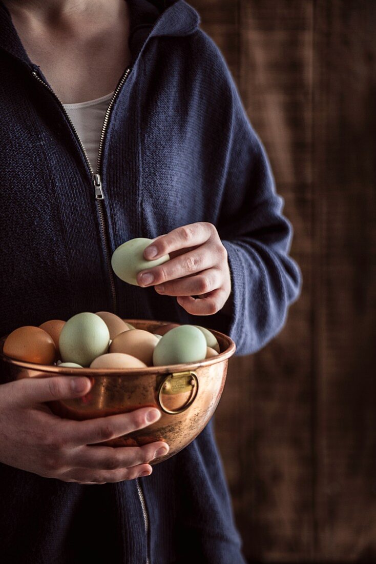 A woman holding a copper bowl of free range eggs