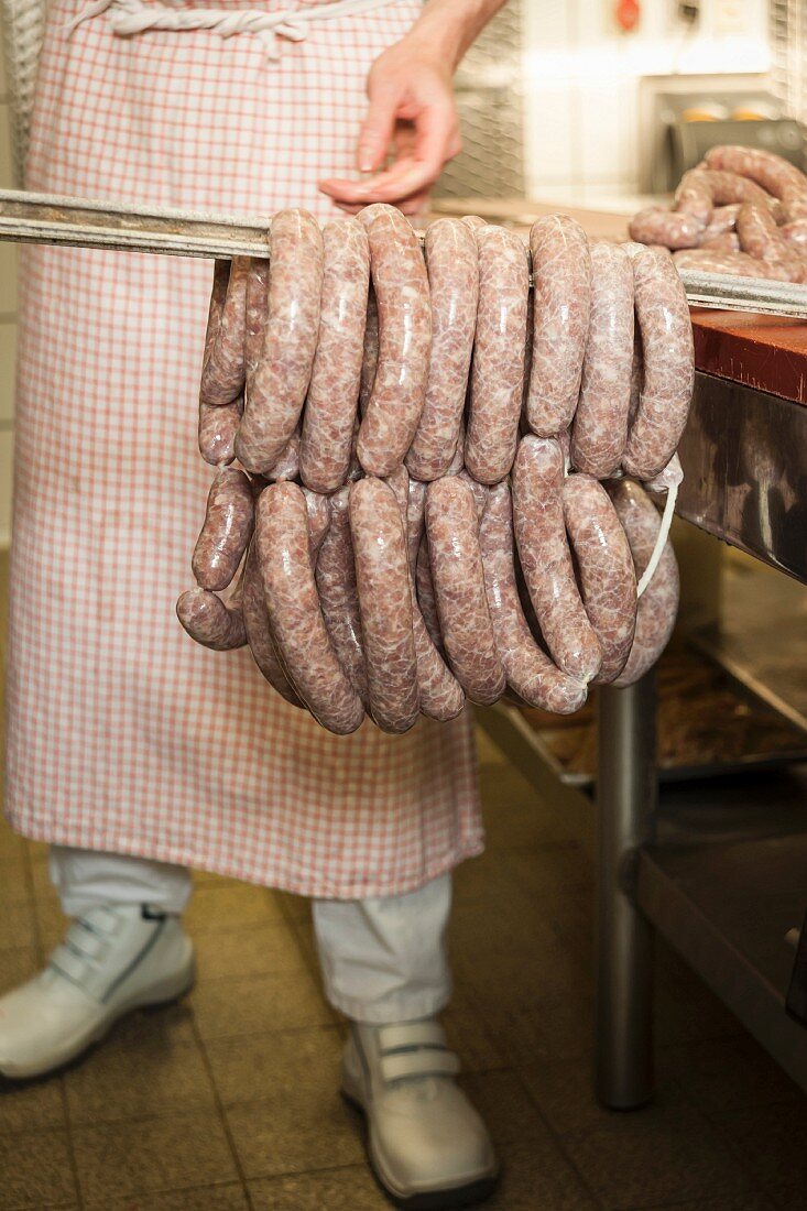 A butcher making sausages: sausages being hung for smoking