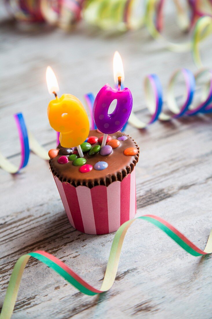 A birthday muffin decorated with chocolate beans and birthday candles