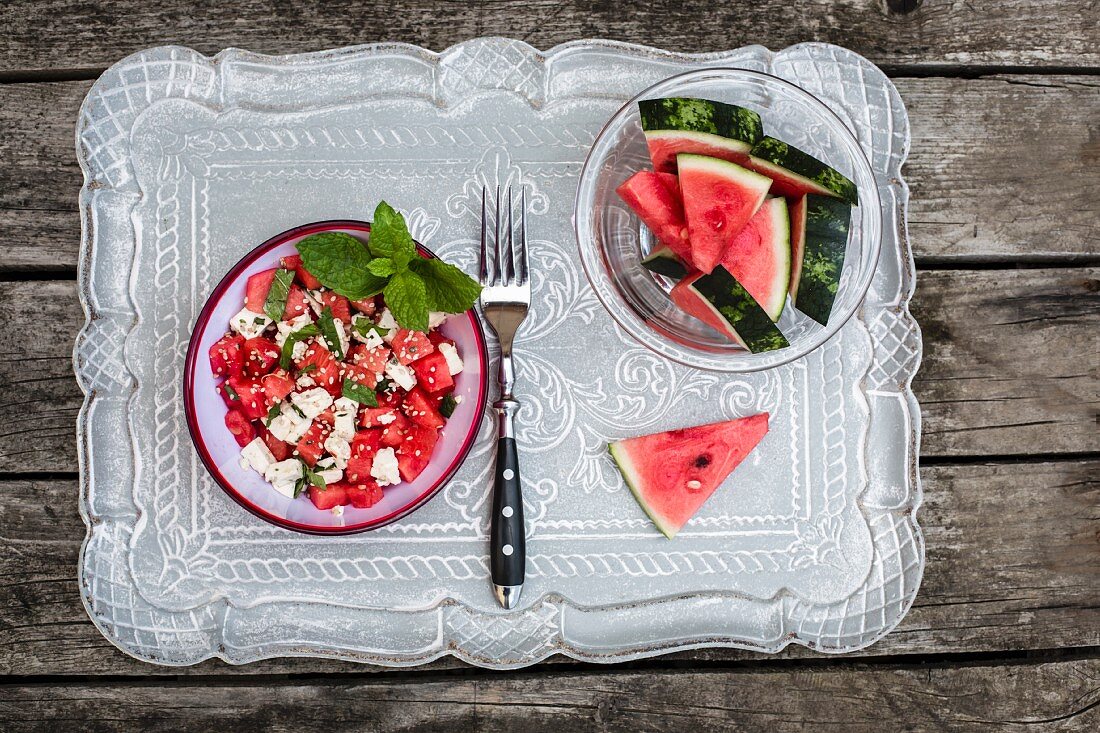 Wassermelonensalat mit Fetakäse, Minze und Sesam auf Holztisch