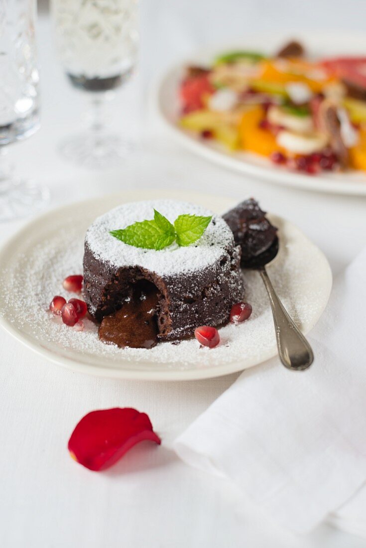 Moelleux au chocolat with pomegranate seeds and icing sugar