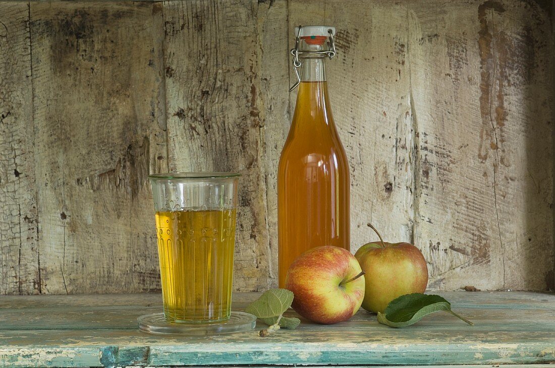 Apfelsirup und Glas Apfelsaft, Äpfel (Jonagold) in einem rustikalen Schrankregal