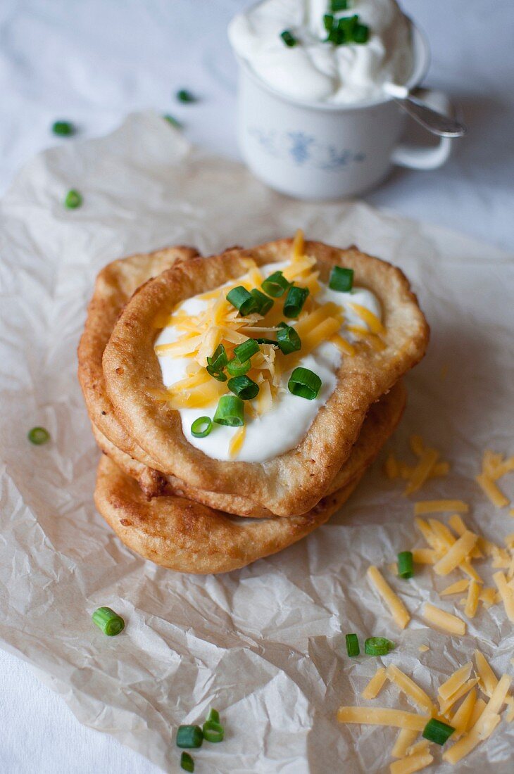 Langos (fried Hungarian flatbread with sour cream, grated cheese and chopped spring onions)