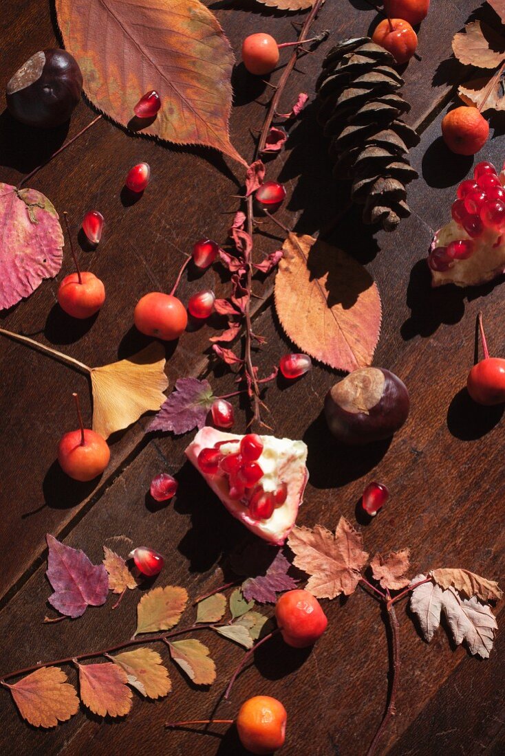 Herbststilleben mit Blättern, Kastanien und Granatapfel