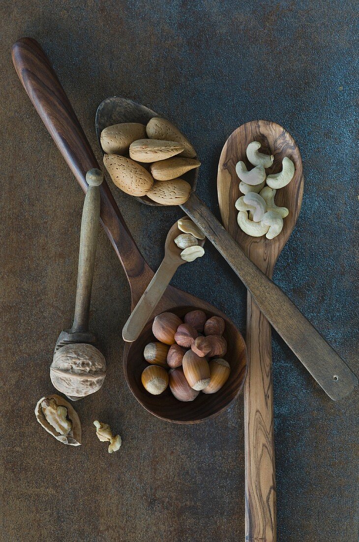 Walnuts, hazelnuts, cashew nuts, peanuts and almonds on wooden spoons