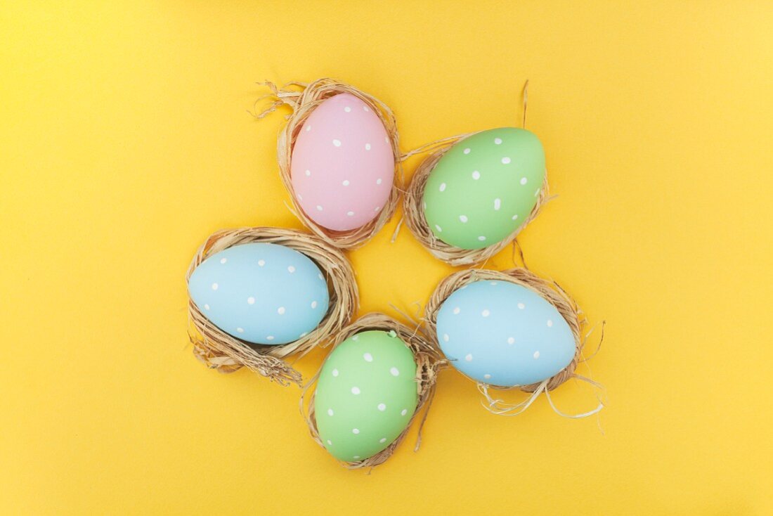 Colourful Easter eggs with white dots on a yellow surface