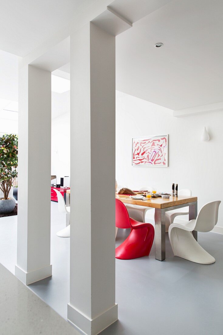 Red and white shell chairs in dining area in open-plan interior