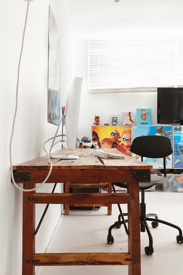 Rustic wooden table against wall and swivel chair in teenager's bedroom