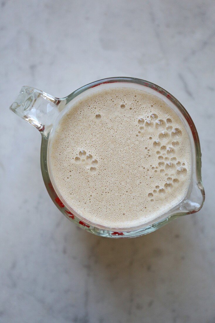 Oat milk in a glass jug on a marble surface