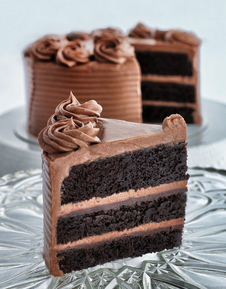 A chocolate cream cake with a slice on a plate