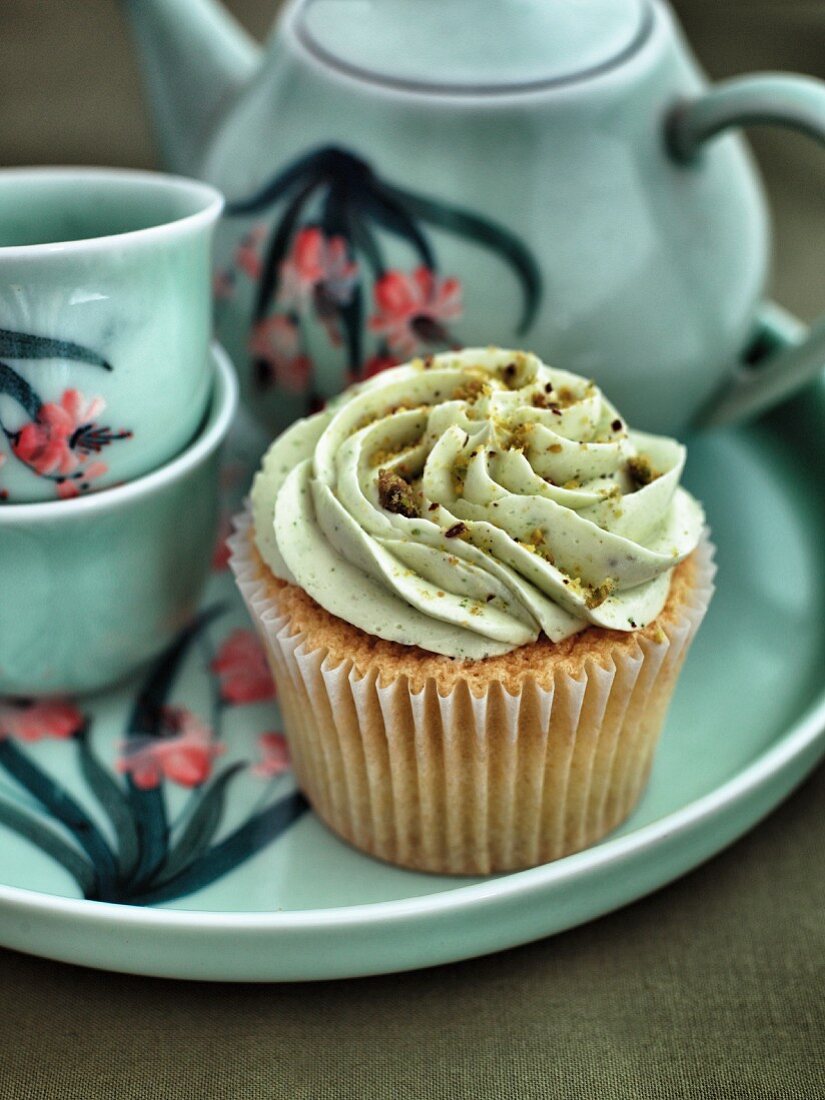 A cupcake with pistachio cream and a tea service