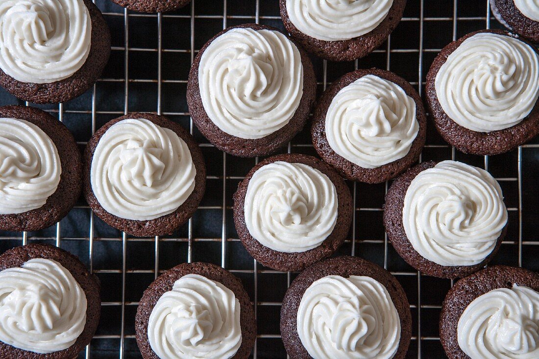 Mini chocolate cupcakes with bttercream on a cooling rack