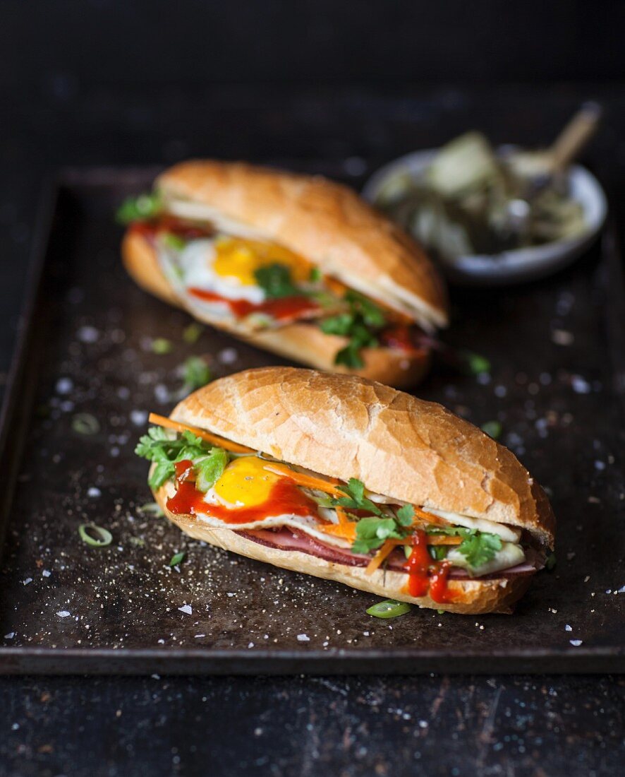Two Bahn Mi (Vietnamese sandwiches) with ham, vegetables and fried egg