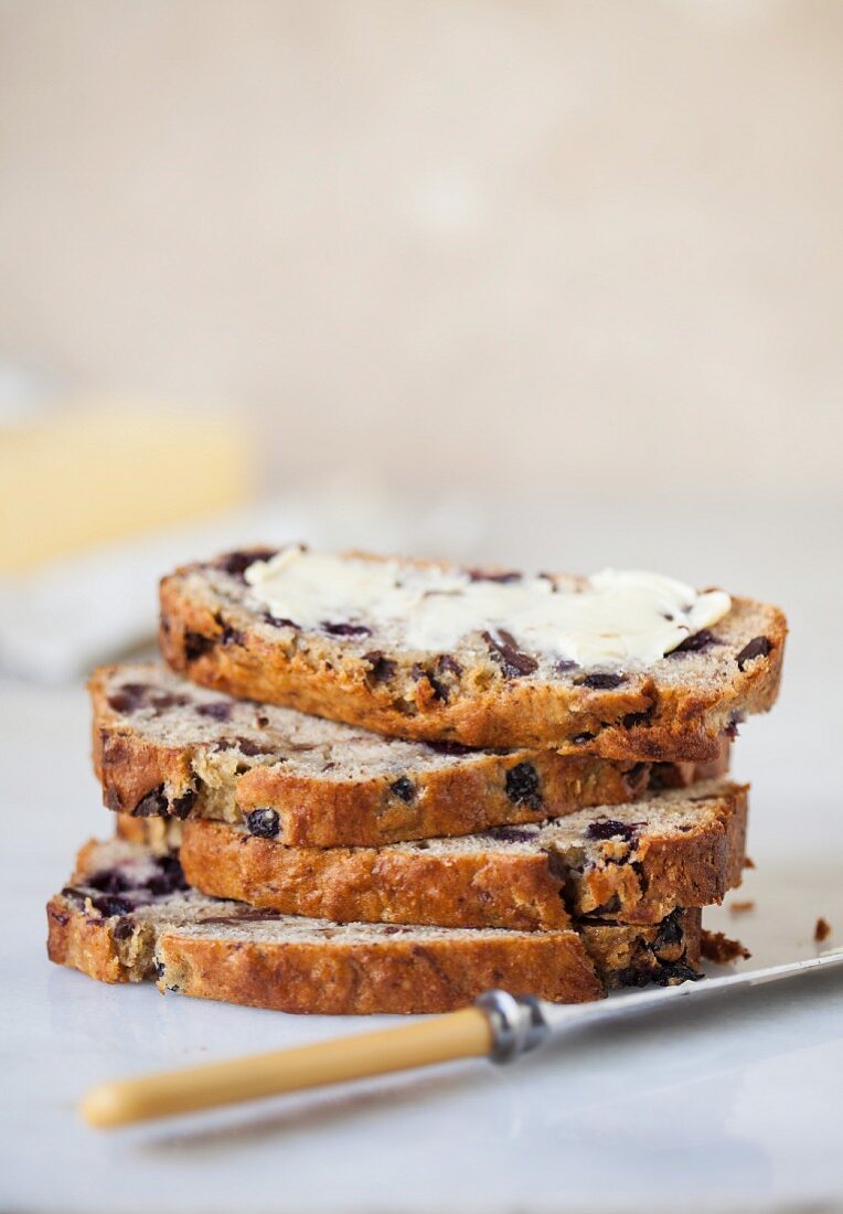 Sliced banana bread with blueberries and chocolate spread with butter