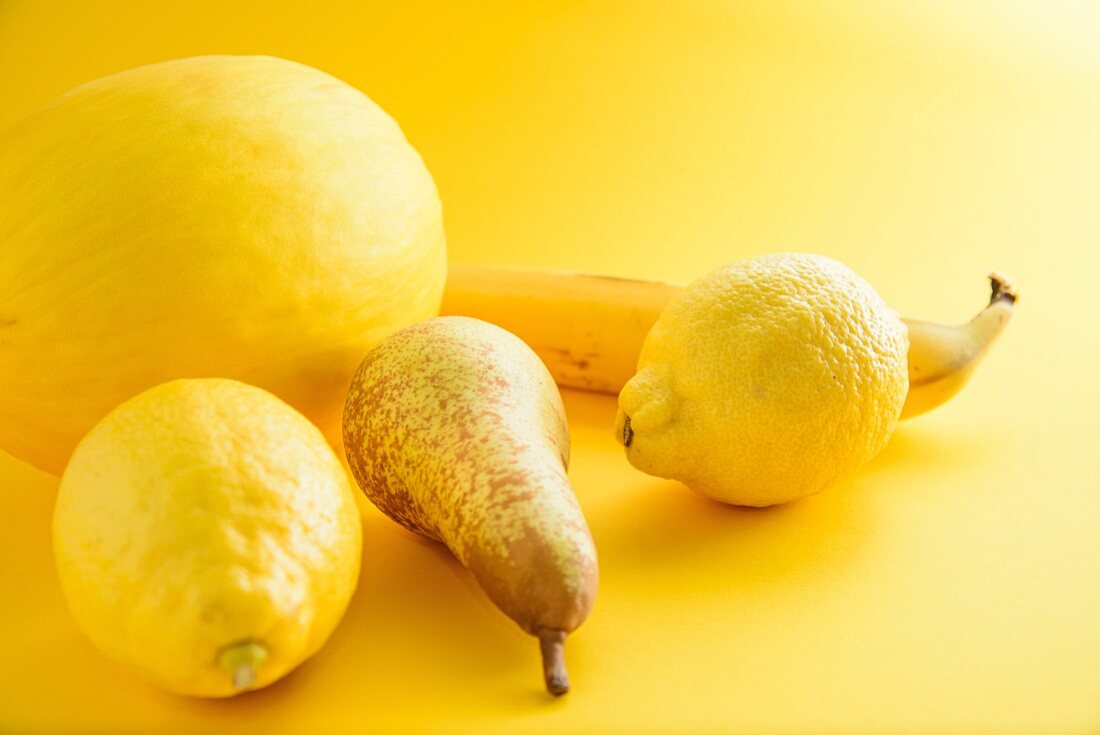 An arrangement of yellow fruits on a yellow surface